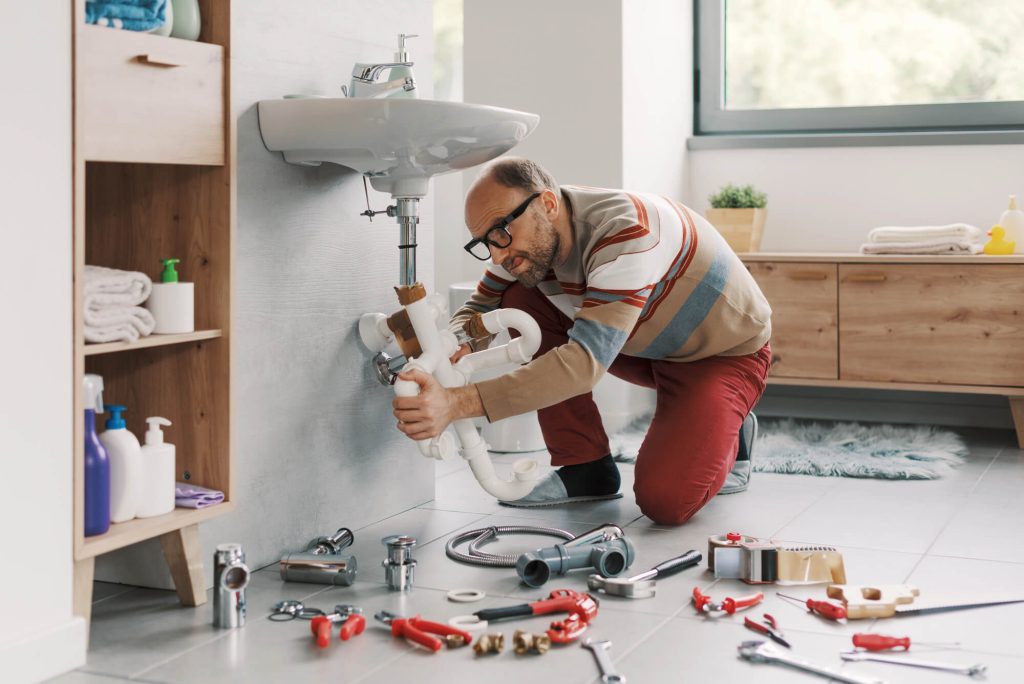 Man failing at DIY plumbing, he is trying to install drain pipes on the bathroom sink